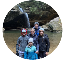 Family posing by a waterfall at Hocking Hills, supporting the Hocking Hills Gives Back cause
