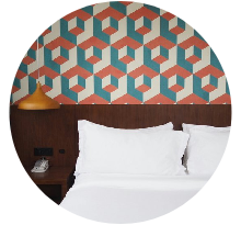 Modern hotel-style room with geometric wallpaper and white linens